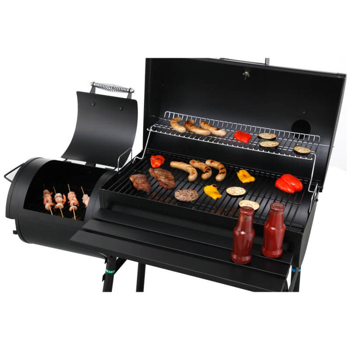Tepro Biloxi Offset BBQ Smoker with meat and vegetables grilling and meat being smoked. Condiments resting on the side table.