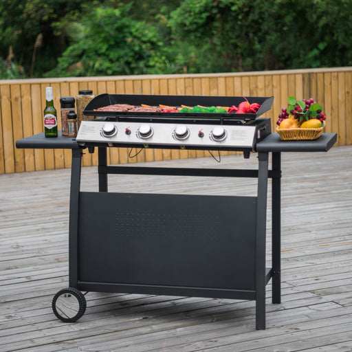 Callow 4 Burner Gas BBQ Plancha resting on Detachable Trolley on a decked garden with meat and vegetables being grilled and condiments resting on side plate