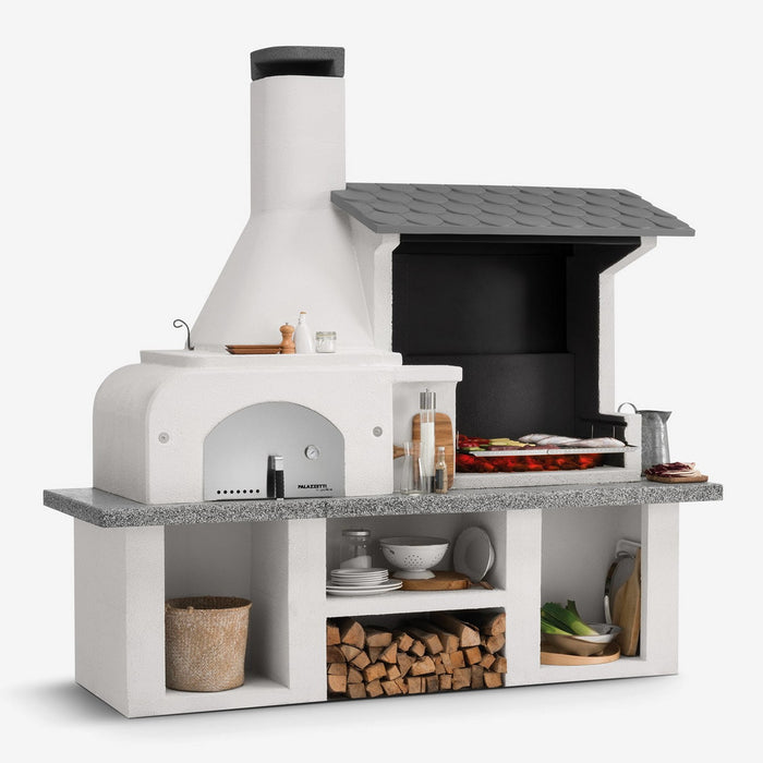 Palazzetti Antille Complete Outdoor BBQ Kitchen with Wood Fired Oven cooking meats and vegetables with condiments, cutlery and logs stored away